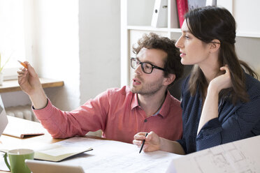 Man and woman discussing at desk in office - FKF02307