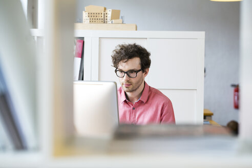 Mann im Büro schaut auf Computerbildschirm - FKF02311