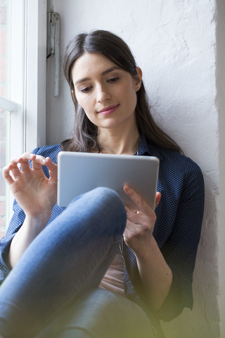 Frau benutzt Tablet am Fenster, lizenzfreies Stockfoto