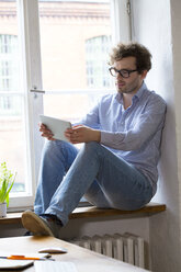 Man using tablet at the window in office - FKF02316