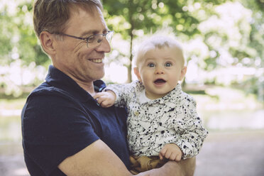 Lächelnder Vater hält staunenden kleinen Jungen im Freien - MFF03527