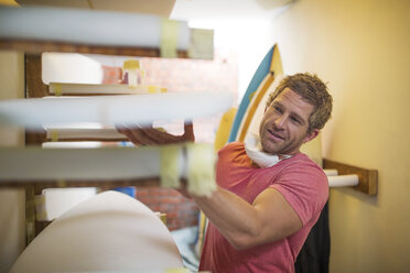 Surfboard shaper workshop, man checking quality of surfboard - ZEF13677