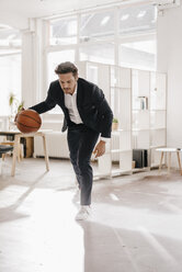 Businessman playing basketball in office - KNSF01293
