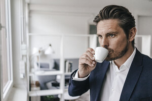 Geschäftsmann trinkt einen Kaffee am Fenster - KNSF01304