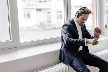 Passionate businessman listening to music on headphones - KNSF01317