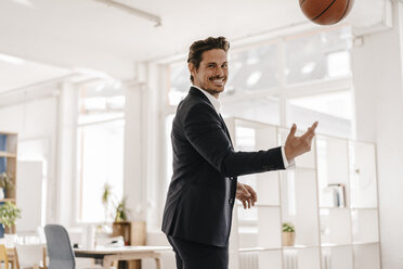 Businessman playing basketball in office - KNSF01339