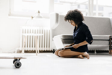 Young woman sitting on floor, using laptop - KNSF01360