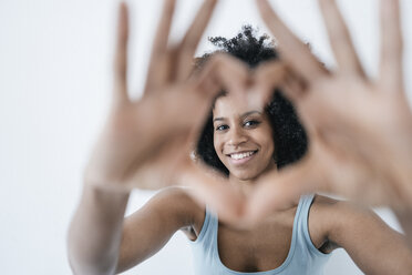 Young woman looking through heart shape finger frame - KNSF01361