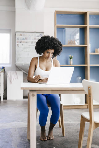 Fitte junge Frau benutzt Laptop zu Hause, lizenzfreies Stockfoto