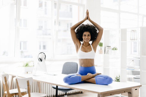 Junge Frau übt Yoga auf ihrem Schreibtisch - KNSF01382