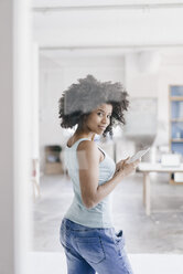 Junge Frau mit digitalem Tablet in ihrem neuen Büro - KNSF01404