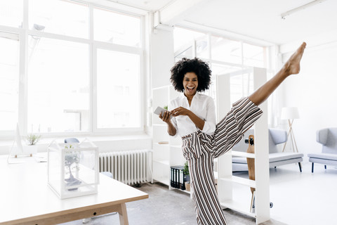 Junge Geschäftsfrau tanzt in ihrem Büro, lizenzfreies Stockfoto