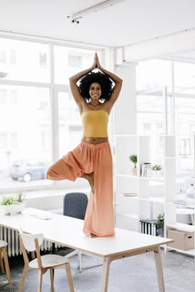 Junge Frau macht Yoga auf ihrem Schreibtisch - KNSF01420