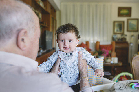Great-grandfather holding a cute baby girl at home stock photo