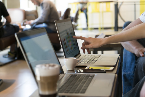 Analyse eines Balkendiagramms auf einem Laptop-Monitor in einem Café, lizenzfreies Stockfoto