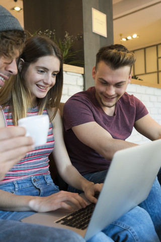 Drei Freunde teilen sich einen Laptop in einem Cafe, lizenzfreies Stockfoto