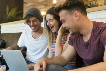 Drei aufgeregte Freunde, die in einem Café auf einen Laptop schauen - KKAF00816