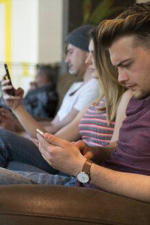 Drei Freunde benutzen ihre Handys in einem Cafe - KKAF00817