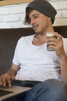 Young man using laptop in a cafe - KKAF00822