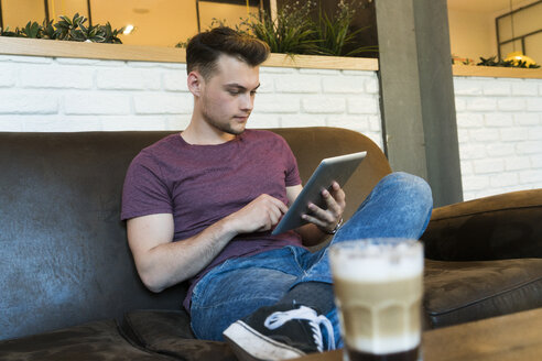 Young man using tablet in a cafe - KKAF00829