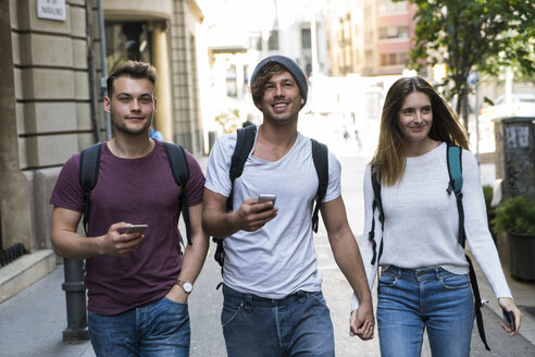 Friends with cell phones walking in the city - KKAF00832