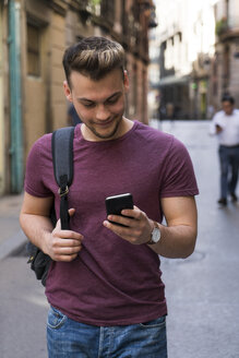 Junger Mann schaut in der Stadt auf sein Handy - KKAF00847