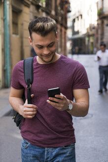 Young man looking at cell phone in the city - KKAF00847