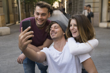 Three happy friends taking a cell phone selfie in the city - KKAF00853