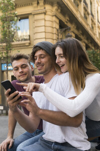 Drei Freunde benutzen ein gemeinsames Handy in der Stadt - KKAF00854