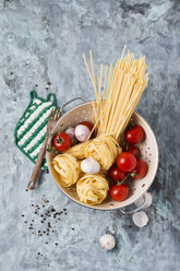 Ungekochte Taglatelle, Spaghetti, Tomaten und Knoblauchzwiebeln im Sieb - MYF01918