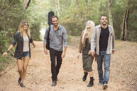 Four happy friends walking on path in the forest stock photo