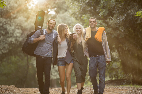 Four happy friends walking on path in the forest - ZOCF00383