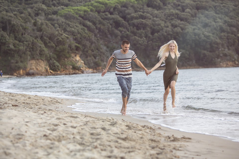 Glückliches Paar beim Laufen am Strand, lizenzfreies Stockfoto