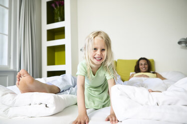 Porträt eines lächelnden kleinen Mädchens auf einem Hotelbett mit ihren Eltern - FSF00911
