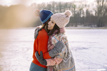 Friends hugging on frozen lake - MFF03532