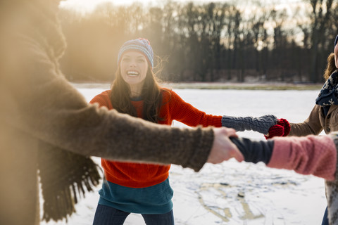 Freunde beim Schlittschuhlaufen im Kreis auf einem zugefrorenen See, lizenzfreies Stockfoto