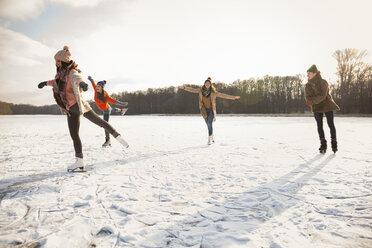 Glückliche Freunde beim Schlittschuhlaufen auf einem zugefrorenen See - MFF03547