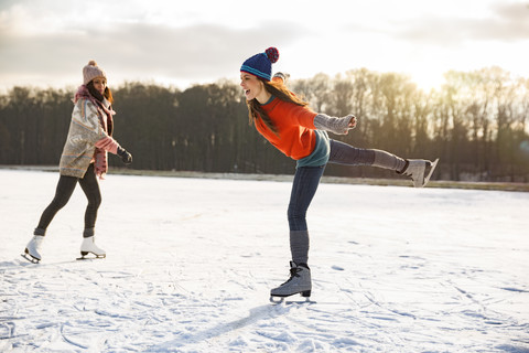 Two women ice skating on frozen lake stock photo
