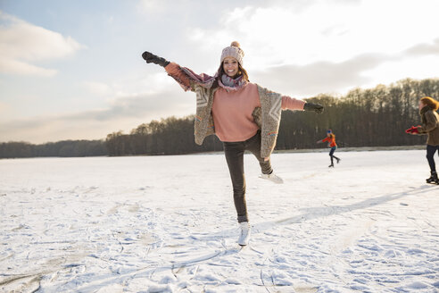 Woman dancing with ice skates on frozen lake with friends - MFF03549