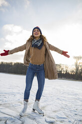 Woman listening to music and ice skating on frozen lake - MFF03558