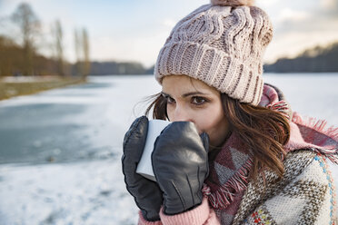 Woman drinking hot beverage from a cup outdoors in winter - MFF03562