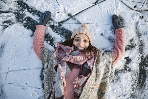 Porträt einer glücklichen Frau, die auf einer gefrorenen Seeoberfläche liegt - MFF03563