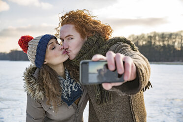 Paar küsst sich auf gefrorenem See und macht ein Selfie - MFF03568