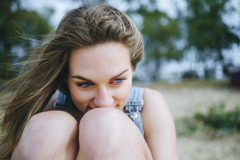 Porträt einer am Strand sitzenden, träumenden Frau, lizenzfreies Stockfoto