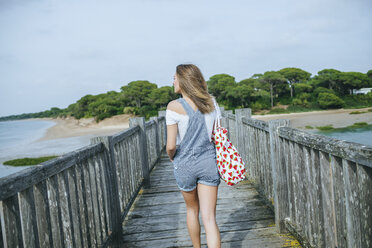 Rückenansicht einer Frau, die auf der Strandpromenade zum Strand geht - KIJF01500