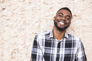 Portrait of happy young man leaning against wall - ABZF02027