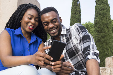 Portrait of smiling young couple looking at cell phone - ABZF02032