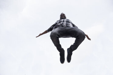 Glücklicher junger Mann, der in die Luft springt - ABZF02034