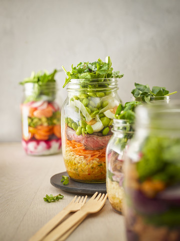 Preserving jar of wheat salad with vegetables, boiled egg and sliced steak stock photo