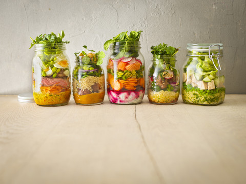 Reihe von fünf Einmachgläsern mit verschiedenen Salaten, lizenzfreies Stockfoto
